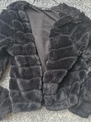 Bolero svart fuskpäls Gina Tricot XXS - Bolero i svart fuskpäls från Gina Tricot. Stl XXS . Knäpps med en liten hake se bild 3. Mkt fint skick