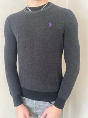 Mörkgrå tröja från Ralph Lauren - Snygg mörkgrå tröja från Ralph Lauren med lila broderad logga på bröstet. Nyskick, inga defekter. Perfekt för en stilren look. Postar samma dag eller inom 24h📦 köp mer än ett plagg för 10% rabbat🤝
