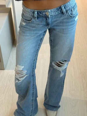 For real low loose jeans Gina Tricot  - Säljer ett par jeans från Gina Tricot som är använda ett par gånger (4-6 gånger) men säljer för att domningen riktigt är min stil längre. Jeansen har klassisk femficksdesign, låg midja och vida ben med hål vid knäna. Perfekta för en avslappnad och trendig look. Materialet är denim i bomul.