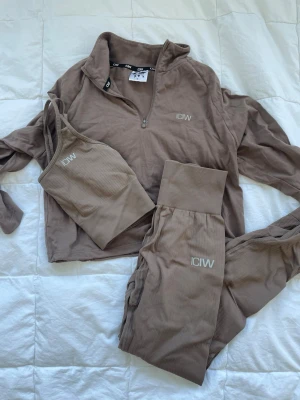 Beige loungewear-set från ICANIWILL - Säljer ett beige loungewear-set från ICANIWILL med croppad ziptröja, ribbad sport-bh och matchande byxor med hög midja. Setet är gjort i mjukt, stretchigt material och har diskret logga på både tröja och byxor. Kan sköpas som set eller separat. Tights: strl XS 300kr  Topp: strl S 250kr Ziptröja: strl XS 250kr. Hela setet: 700kr