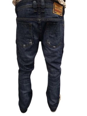 Diesel jeans - Säljer ett par klassiska blå jeans från Diesel industri med raka ben och slitna detaljer. Jeansen har fem fickor, knappgylf och en snygg vintage look med ljusa partier och whiskers. Tillverkade i slitstark denim som ger en cool och avslappnad stil. Uppsydda för att passa 30-längd! Storlek 28 i midjan.