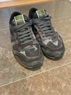 Valentino rockrunner - Snygga blå/gröna sneakers från Valentino Garavani med gröna detaljer på plösen och gråsvarta skosnören. Skorna har en klassisk låg siluett och är tillverkade i en mix av mocka och textil. Perfekta för dig som gillar streetwear och exklusiva märken.