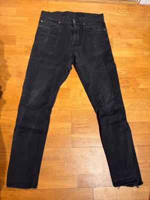 Svarta raka jeans från tiger of sweden  - Säljer ett par svarta jeans med rak passform från tiger of Sweden . Jeansen har klassisk femficksdesign och knappgylf. Materialet är denim i bomull och färgen är tvättad svart för en avslappnad look. DEFEKT slutet på höger ben har sömmarna lossnat går att laga