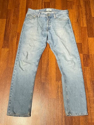 Ljusblå raka jeans från Jack and Jones - Säljer ett par ljusblå jeans från Jack and Jones med klassisk rak passform och fem fickor. Jeansen har en stilren look med diskret tvätt och läderpatch bak i midjan. Perfekta för en avslappnad och trendig stil. Pris kan diskuteras!