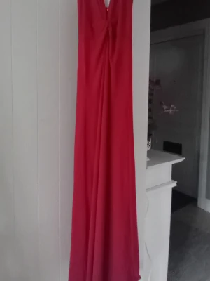 Mörkröd långklänning  - Jättefin mörkröd figursydd långklänning med lätt rynkat tyg vid ringningen. Mycket bra skick då klänningen aldrig är använd utan endast provad. Obs vissa bilder förljusar då klänningen går mer åt mörkröd.
