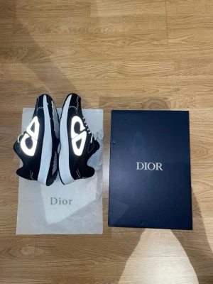 Svarta b30s sneakers med reflexdetaljer - Snygga svarta sneakers b30 med vita och reflekterande detaljer på sidorna. Skorna har en chunky vit sula och vita skosnören. Perfekta för dig som vill sticka ut med exklusiva och trendiga sneakers.