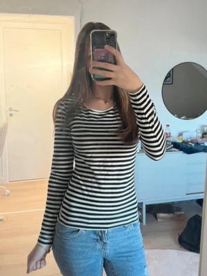 Randig långärmad topp ifrån H&M - Snygg långärmad topp med svartvita ränder och rund halsringning. Tillverkad i mjuk bomull som sitter skönt mot kroppen. Perfekt att styla med jeans eller kjol för en enkel men trendig look. Storlek S. Postar inom 1-3 dagar💕. Inga defekter!