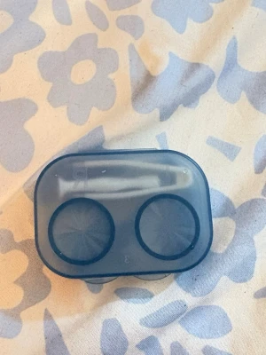 Blå kontaktlinsbehållare i plast - Praktisk blå kontaktlinsbehållare i plast med genomskinligt lock. Behållaren har två separata fack märkta med R och L för höger och vänster lins. Perfekt för att förvara och skydda linser när du är på språng.