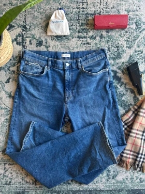 Blå jeans från GANT - Säljer ett par klassiska blå jeans från GANT med fem fickor och normal passform. Jeansen har en snygg tvätt och detaljer i kontrastsömmar. Tillverkade i mjuk denim som ger en skön känsla och passar till många olika stilar.