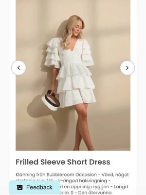 Studentklänning Bubbleroom  - Superfin vit studentklänning från Bubbleroom med flera lager volanger och v-ringad hals. Klänningen har korta volangärmar och markerad midja men även  en vacker rygg. Materialet är vävt och något stretchigt. Helt oanvänd med alla lappar på. Säljer för att jag hittade en annan studentklänning som passade mig mer och har då inget behov av denna! 🌸🩷