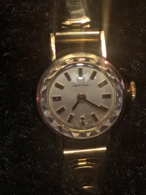 Guldpleterad vintageklocka Certina - Stilren guldfärgad vintageklocka från Certina med rund urtavla och markerade timindex med 20microne guld.. Klockan har ett klassiskt armband i metall och elegant fasettslipad glasring. Perfekt accessoar för dig som gillar tidlös design. Vrid timvisaren och klockan kommer igång. 