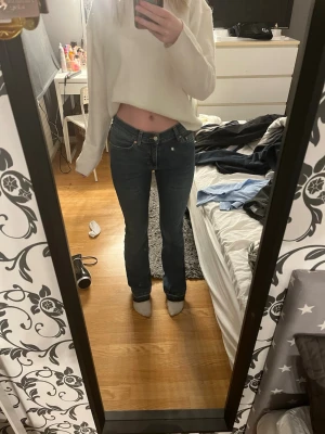 Mörkblå bootcut jeans - Säljer ett par mörkblå bootcut jeans med klassisk femficksdesign och låg midja. Jeansen har en snygg tvätt och raka ben som går ut lite nedtill. Perfekta till en avslappnad stil och passar till det mesta. Inga synliga loggor eller märken.