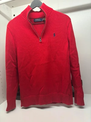 Ralph Lauren half-zip - Röd stickad tröja med halv dragkedja och hög krage från Polo Ralph Lauren. Tröjan har ett blått broderat logomärke på bröstet, ribbstickade muddar och nederkant. Perfekt för lager-på-lager och snygg till jeans. Har du några frågor så svarar jag snabbt! Pris kan diskuteras vid snabb affär!🙌🔥💸