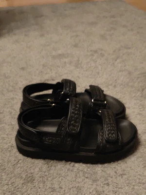 Svarta chunky sandaler med kardborre - Snygga svarta sandaler med breda remmar och kardborrestängning. Sandalerna har en chunky sula och detaljer i flätad look på remmarna. Perfekta för en trendig och bekväm stil. Passar till många olika outfits och är lätta att ta på och av.