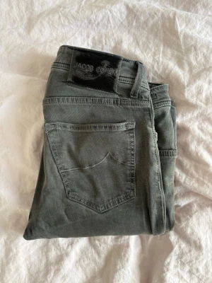 Grå jeans från Jacob Cohen - Snygga grå jeans från Jacob Cohen med klassisk femficksmodell och diskret logga på bakfickan. Tillverkade i exklusivt tyg med italienskt hantverk. Perfekta för dig som gillar stilrena och tidlösa plagg.