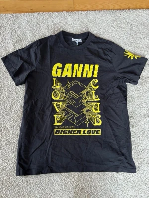 Svart Ganni t-shirt med gul print - Svart t-shirt från Ganni med gul grafiskt tryck.