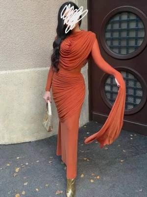 Klänning HOUSE OF CB - Snygg långklänning med draperad design och lång ärm. Klänningen har en elegant omlottkänsla och markerad midja, samt en slits på sidan. Perfekt för dig som vill sticka ut med en unik och trendig look. Fått otroligt mycket komplimanger och har två av de i storlek M 