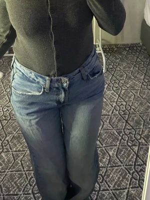 Ljusblå raka jeans med hög midja - Säljer ett par ljusblå jeans med rak passform och hög midja. Jeansen har klassisk femficksdesign och stängs med dragkedja och knapp. Perfekta för en avslappnad och trendig look.