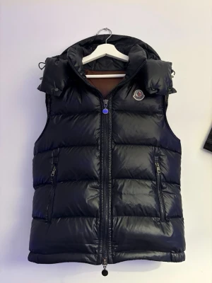 Moncler väst - Moncler väst i färgen marinblå med en insida av färgen mörkbrunt/vinröd. Storlek M och passar folk som är mellan 168-182 cm.  Ser helt ny ut och är använd max 8 ggr. Skriv om ni har frågor ☺️