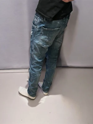 Blå replay anbass slimfit - Säljer ett par blå jeans från replay med slitningar och modellen är slim fit. Jeansen har fem fickor, tydliga slitdetaljer och en avslappnad passform. Perfekta för en casual look och passar till det mesta. Klassisk blå tvätt och coola detaljer. Jeansen är i strl W31 L32. Jeansen har sjukt snygga slitningar. Skriv vid fler frågor