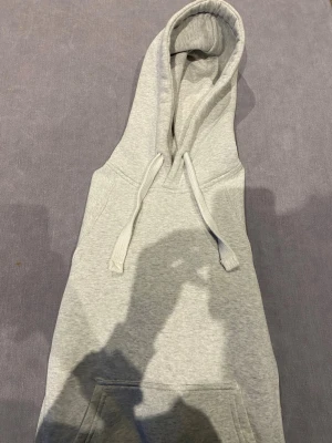 Hoodie från russemerch  - En stilren ljusgrå hoodie med klassisk huva och dragsnören. Hoodien har en stor magficka framtill och ribbade muddar vid ärmar och nederkant. Perfekt för en avslappnad och casual look. Tillverkad i mjukt sweatshirtmaterial för extra komfort. Storleken är XS men passar även S.