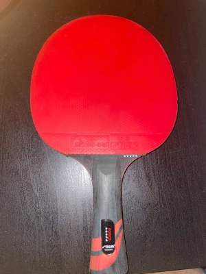 Röd pingisracket från Stiga - Säljer en pingisracket från Stiga med röd gummiyta och svart handtag med röda detaljer. Racketen har fem stjärnor markerade på handtaget och är perfekt för dig som vill ta ditt spel till nästa nivå. Passar både till träning och match.