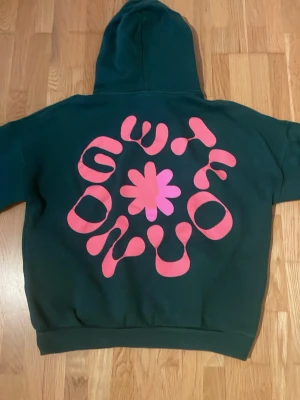 Mörkgrön hoodie med rosa tryck från pull&bear - Grön tröja med rosa tryck från pull&bear äldigt bra skick inga slitnings eller fläckar.