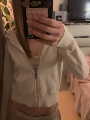 Vit hoodie med dragkedja från SOC - Säljer en vit hoodie från SOC i storlek 34 men passar även S. Hoodien har dragkedja framtill, huva och ribbade muddar vid ärmsluten. Materialet är mjukt och skönt, perfekt för chill dagar. Enkel och stilren design som passar till det mesta.