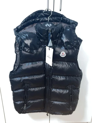 Svart dunväst från Moncler - den är strl 1 som är S. helt ny kommer med allt i bilden tar byten beror på om jag gillar det eller inte den är helt ny aldrig använd pris kan diskuteras vid snabba affär 