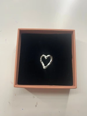 Silvrig hjärtring  - Superfin justerbar hjärtsilvrr ring. Använd väldigt lite så har inga skador eller liknande! Skickar så fort jag kan!