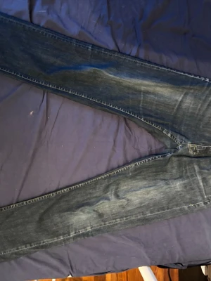 Mörkblå slim fit jeans från tiger of sweden - Säljer ett par mörkblå slim fit jeans med klassisk femficksdesign och snygga slitningar. Jeansen har en smal passform och är tillverkade i denim med lätt stretch för extra komfort. Perfekta till en avslappnad stil.