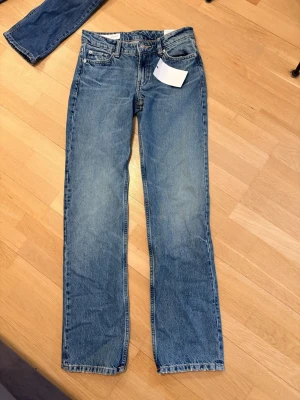 Zara jeans låg midja  - Snygga blå jeans med rak passform och klassisk femficksdesign. Jeansen har normalhög midja och är tillverkade i ett slitstarkt denimtyg. Perfekta för en avslappnad och tidlös stil.
