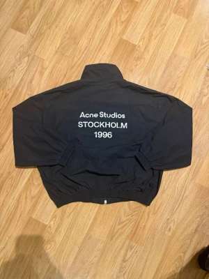 Acne Studios Jacka  - Svart vindjacka från Acne Studios med tryck 'Acne Studios STOCKHOLM 1996' på ryggen. - Helt Ny knappast använd- 10/10 skick - Passar storlek S - Redo att fraktas idag 🚚