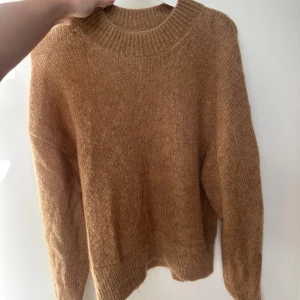 Brun stickad tröja i mohair - Mysig brun stickad tröja med rund halsringning och långa ärmar. Tröjan är gjord i 50% mohair,31% polyamid, 19% lä