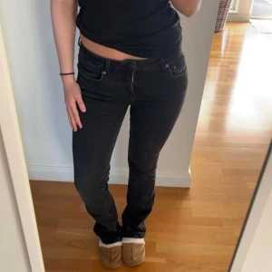 Svarta bootcut jeans med låg midja - Snygga svarta jeans med bootcut-modell och låg midja. Jeansen har klassisk femficksdesign, dragkedja och knapp framtill. Perfekta för dig som gillar en stilren look med lite utsvängda ben. Materialet är mjukt och stretchigt för skön passform.
