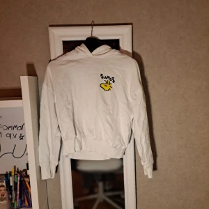 Vit Peanuts hoodie med tryck - Vit hoodie från Peanuts med tryck fram och stora Peanuts-gänget bak. Mjuk bomullskänsla, huva och ribbade muddar. Perfekt för dig som älskar serier och vill ha en chill och snygg look. Ifrån Zara.