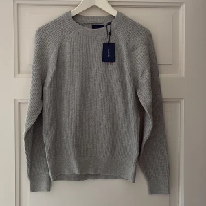 Grå ribbstickad tröja från GANT - Säljer en snygg grå ribbstickad tröja från GANT. Aldrig använd. Tröja för ungdom/kille. Nypris 850kr säljes för 500kr