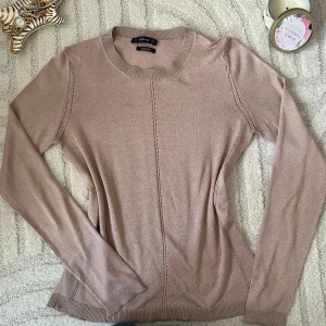 Beige stickad tröja från Zara - Supersnygg beige stickad tröja från Zara med lång ärm och rund hals. Tröjan har dekorativa sömmar framtill och längs sidorna som ger en stilren look. Perfekt att matcha med jeans eller kjol för en clean vibe.