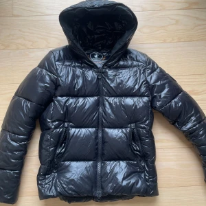 Svart pufferjacka från Save The Duck - Säljer en tvär fet svart pufferjacka från Save The Duck. Perfekt nu inför hösten och vintern. Jackan har storleken S och värmer dig hela vintern. Vid fler frågor och funderingar är det bara att höra av sig 