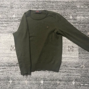 Merinoullströja från Morris - Säljer en olivgrön tröja från Morris i 100% merinoull. Tröjan har rund halsringning, diskret broderad logga på bröstet och ribbade muddar vid ärmslut och nederkant. Perfekt för lager-på-lager under kyliga dagar. Riktigt stilren och fräsch. Tröjan är originellt i S men tvättades fel en gång så den passar som XS. Tveka inte vid ytligare frågor😉🙌