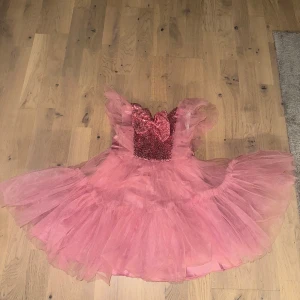 Rosa tyllklänning med paljetter - Superfin rosa klänning i tyll med voluminös kjol och glittrig paljettöverdel. Klänningen har en stor rosett framtill och vackra volangärmar. Perfekt för dig som vill sticka ut med en riktigt drömmig look. För 4-5 år flicka 👧 inköpt för 499