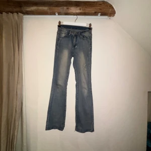 Blå bootcut jeans med råa kanter - Säljer ett par blå bootcut jeans med låg midja och slitna, råa kanter nertill. Jeansen har klassisk femficksdesign, lätt tvättade detaljer och är i ett mjukt denimtyg. Perfekta för dig som gillar en avslappnad och trendig look. Säljer då dom är förstor för mig över lår. Dom är mycket strechiga också. Använda mycket är dom.