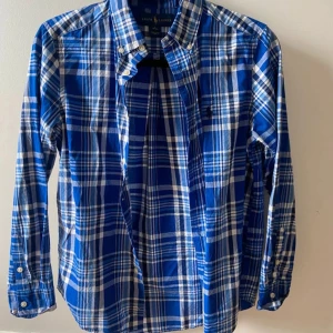 Blårutig skjorta från Ralph Lauren XS - Tvärfet blårutig skjorta från Ralph Lauren med klassisk button-down krage och broderad logga på bröstet. Skjortan är stl L i barnstorlek vilket motsvarar XS i vuxenstorlek. 