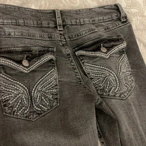 Grå jeans med broderade bakfickor - Snygga grå jeans från Gina med unika broderade detaljer på bakfickorna och kontrastsömmar. Jeansen har klassisk femficksdesign, raka ben och normal midja. Perfekta för dig som vill sticka ut med coola detaljer och en avslappnad vibe. Dom är 170 i storlek 