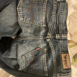 Levi's jeans - Klassiska Levi's 501 jeans i mörkblå tvätt med raka ben/bootcut och normal passform. Snygga kontrastsömmar, femficksmodell och ikonisk läderpatch bak i midjan. Tillverkade i slitstarkt jeanstyg av bomull. Perfekta för en avslappnad och cool look.