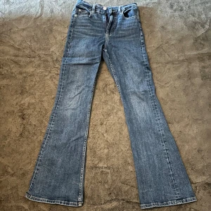 Gina Tricot bootcut jeans blå denim  - Klassiska Gina tricot jeans i blå denim med bootcut passform. Snyggt utsvängda ben och femficksmodell. 