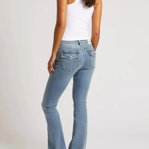 Ljusblå bootcut jeans från True Religion - Snygga ljusblå jeans från True Religion med bootcut passform. Jeansen har klassiska fem fickor, dekorativa sömmar och lock på bakfickorna med silverfärgade knappar. Tillverkade i stretchig denim för en bekväm känsla.