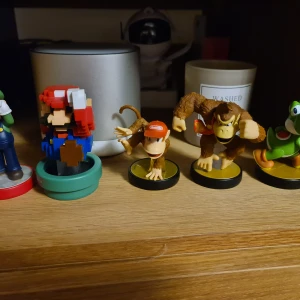 Nintendo Amiibo Super Mario Collection - Samling av Nintendo Amiibo-figurer: Mario (8-bit), Luigi, Diddy Kong, Donkey Kong och Yoshi. Figurerna är i mycket fint skick, perfekta för samlare eller användning med kompatibla Nintendo-spelkonsoler. Inga synliga defekter eller slitage.