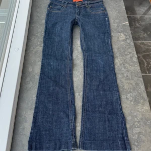 Blå bootcut jeans med broderade fickor - Snygga blå jeans med bootcut-modell och coola broderade detaljer på bakfickorna. Midjemått: 38 cm, Innerbenslängd: 77 cm