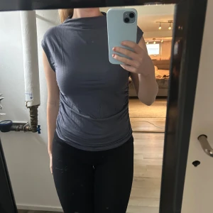 Mörkgrå ärmlös topp med hög hals - Säljer en stilren mörkgrå topp med hög hals och ärmlös design. Toppen har en tight passform och är tillverkad i ett mjukt, stretchigt material som sitter snyggt mot kroppen. Perfekt för dig som gillar minimalistisk och clean stil.🩷Strl: L men passar bäst M,S🩷